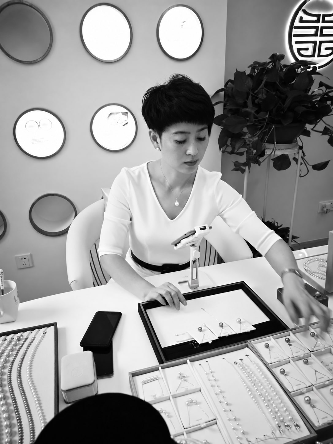 An archival working photograph of pearl jewellery being arranged at a display table.